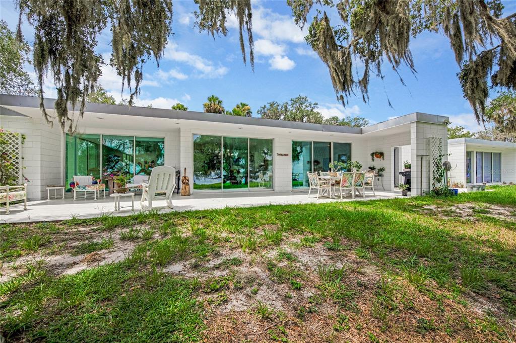 A white, flat-roofed house with large glass sliding doors opens onto a concrete patio — 2600 FORT LANE ROAD, GENEVA, FL