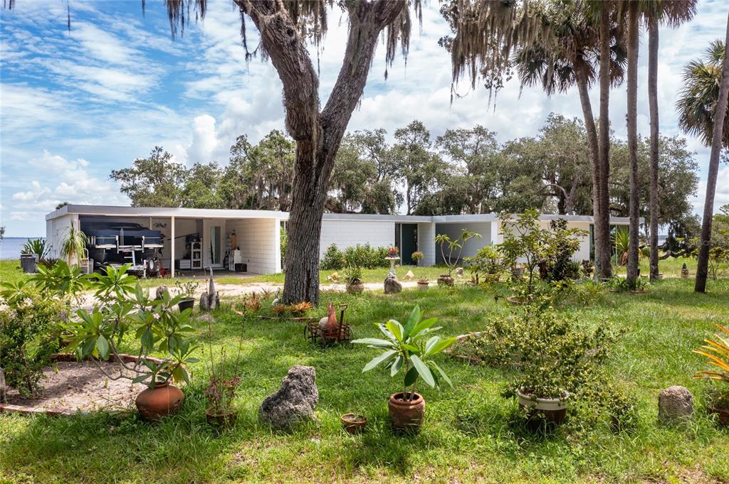 A single-story mid-century modern home with a carport sits on a grassy, tree-filled lot — 2600 FORT LANE ROAD, GENEVA, FL