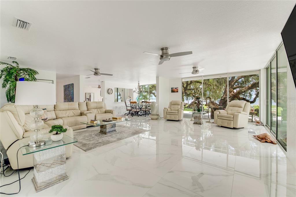 A spacious living room features white tile floors, cream-colored leather furniture, and large sliding glass doors — 2600 FORT LANE ROAD, GENEVA, FL