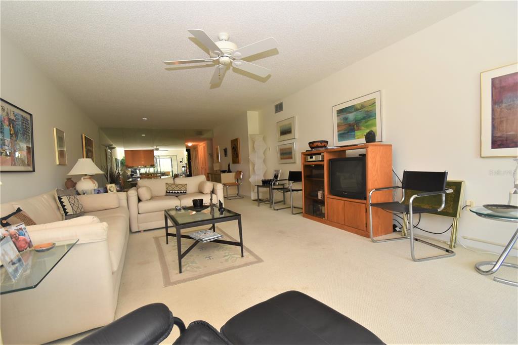 A living room features a beige sofa, a glass coffee table, and a wooden media console — 1526 PELICAN POINT DRIVE UNIT BA144, SARASOTA, FL