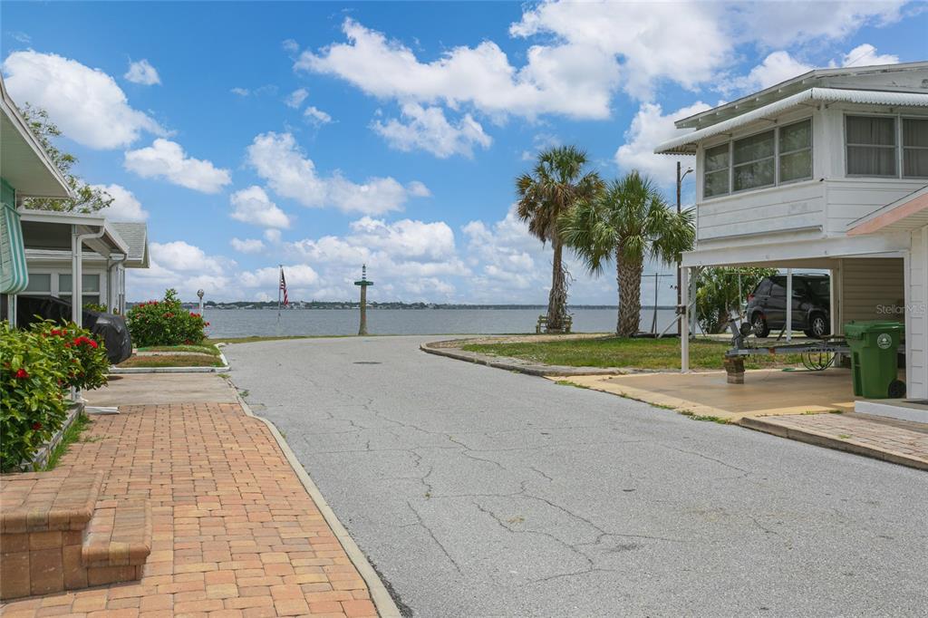 A paved street leads toward a waterfront view between two residential buildings with palm trees — 14 LAFAYETTE STREET, BRADENTON, FL