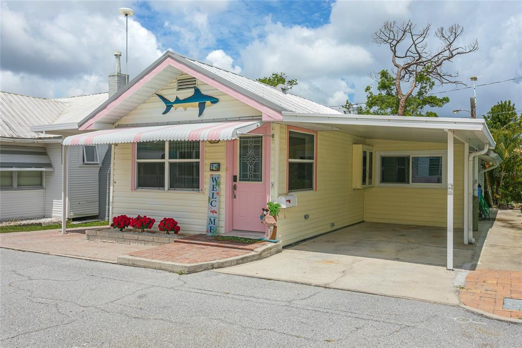 A yellow single-story house with a pink door, shark decor, and an attached carport — 14 LAFAYETTE STREET, BRADENTON, FL