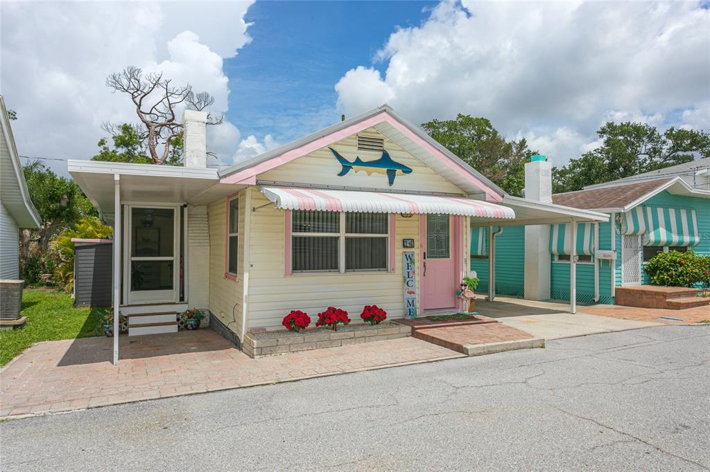A yellow cottage with a shark decoration, pink trim, and a covered carport — 14 LAFAYETTE STREET, BRADENTON, FL