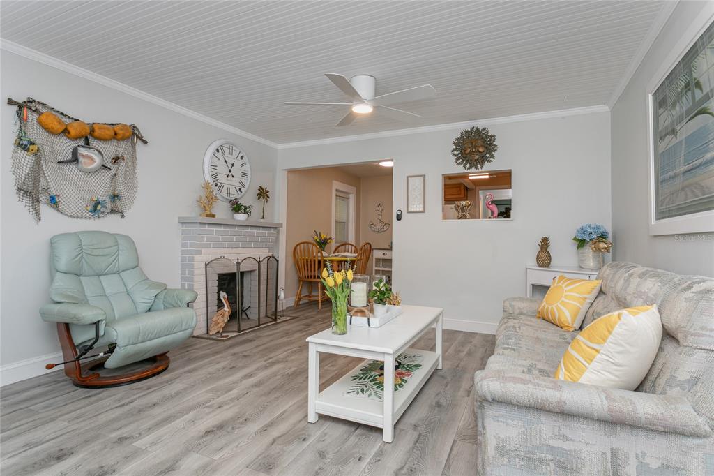 A living room features a brick fireplace, light wood-look flooring, and coastal-themed decor — 14 LAFAYETTE STREET, BRADENTON, FL
