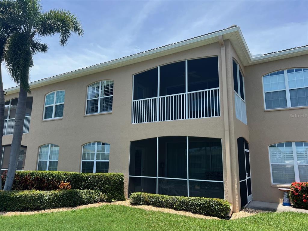 A two-story building exterior features screened-in balconies and patios with white railings and landscaping — 6444 7TH AVENUE CIRCLE W UNIT 6444, BRADENTON, FL