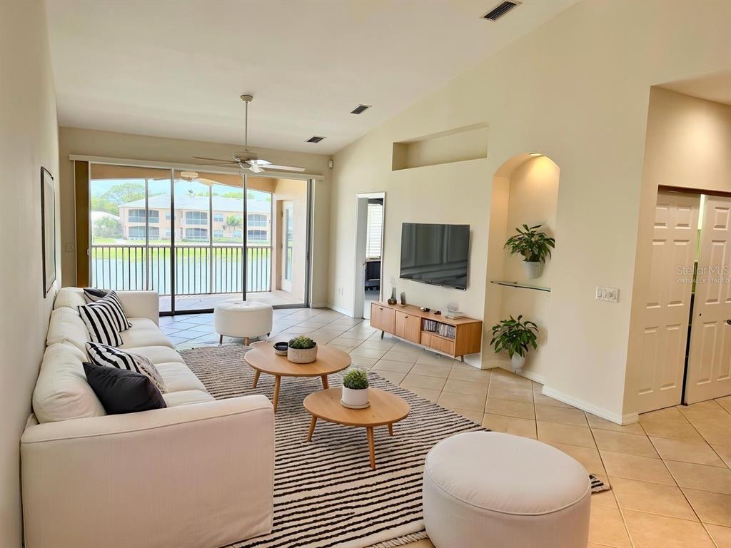 A living room with a white sofa, two coffee tables, and a wall-mounted television — 6444 7TH AVENUE CIRCLE W UNIT 6444, BRADENTON, FL