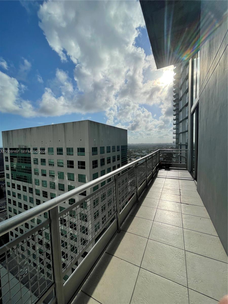 A high-rise balcony features a metal railing and tiled flooring overlooking a neighboring office building — 690 SW 1st Ct # 3115, Miami FL 33130, MIAMI, FL