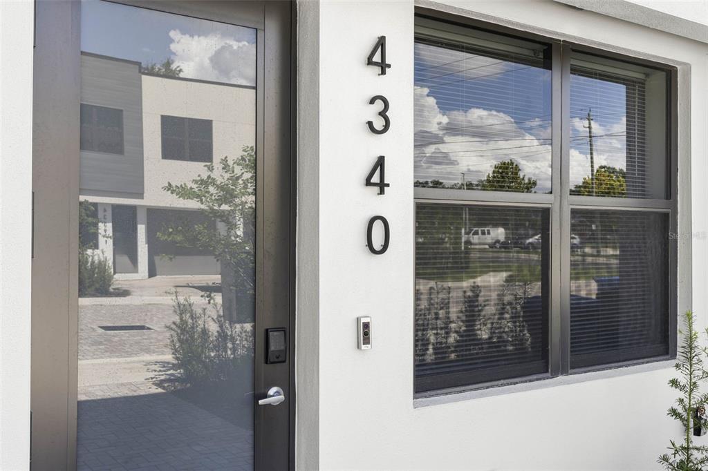 A modern building entrance features a glass door, a doorbell camera, and vertical house numbers — 4340 VILLA ALINA COURT, TAMPA, FL