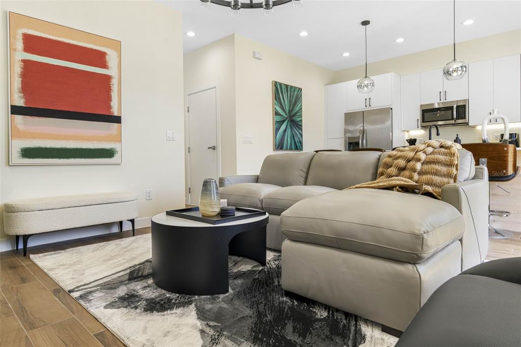 A modern living room features a grey sectional sofa, a round coffee table, and white cabinetry — 4340 VILLA ALINA COURT, TAMPA, FL