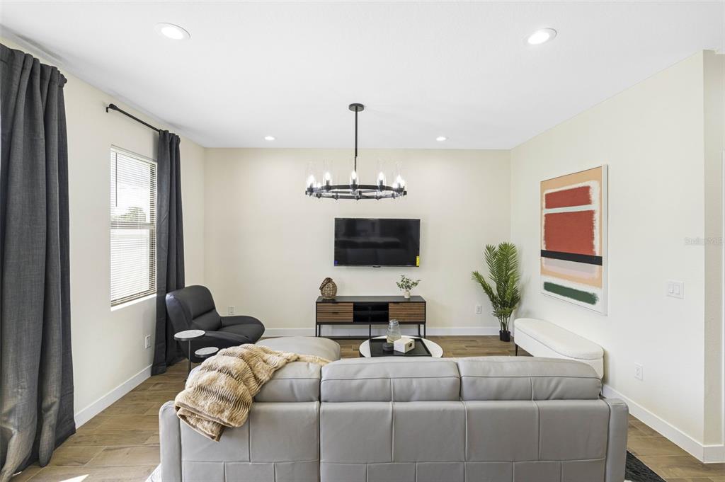 A living room features a gray sectional sofa, a wall-mounted television, and a modern chandelier — 4340 VILLA ALINA COURT, TAMPA, FL