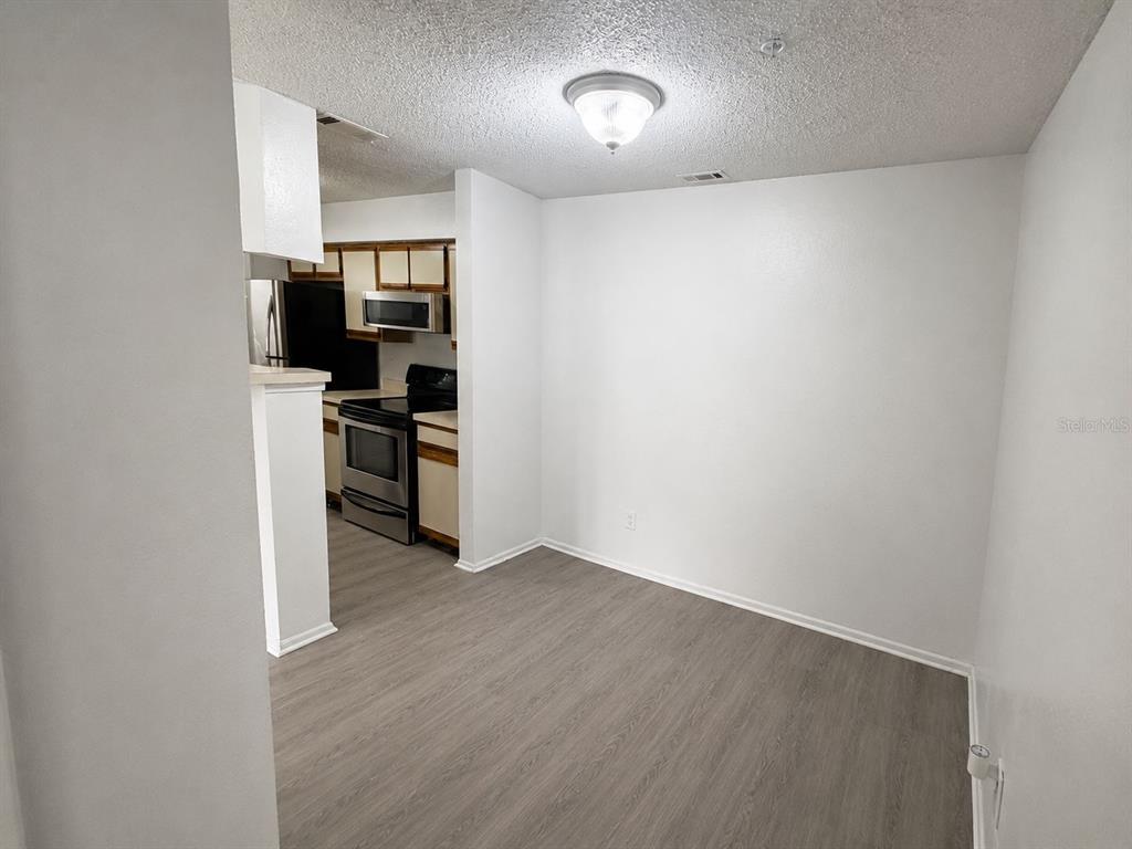 A dining area with light wood-look flooring opens into a kitchen with wood cabinets — 249 AFTON SQUARE UNIT 107, ALTAMONTE SPRINGS, FL