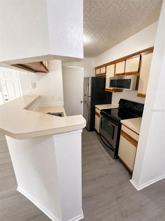 A kitchen features light-colored cabinets, stainless steel appliances, and a peninsula counter — 249 AFTON SQUARE UNIT 107, ALTAMONTE SPRINGS, FL