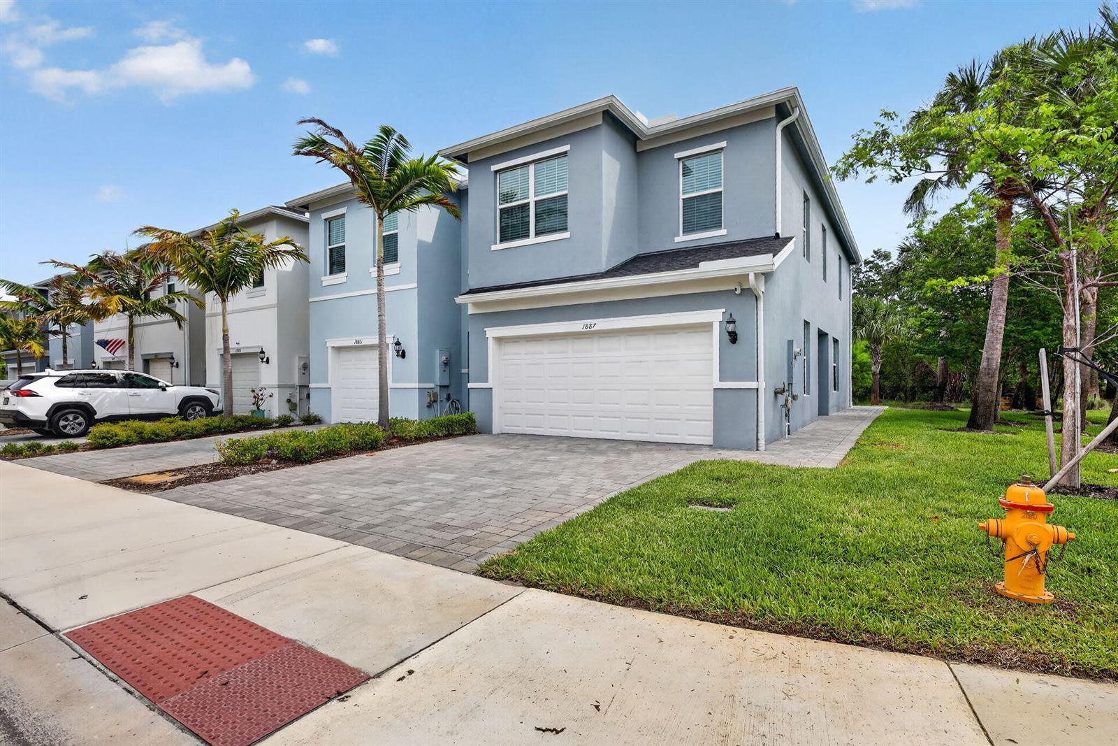 A blue two-story townhouse with a white garage door and a fire hydrant nearby — 1887 SE Ocean Cove Way, Stuart FL 34996, STUART, FL
