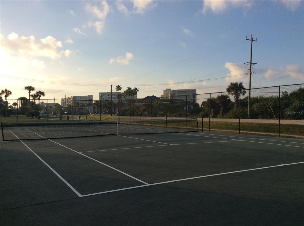 A tennis court with a net is enclosed by a chain-link fence outdoors — 4849 SAXON DRIVE UNIT C102, NEW SMYRNA BEACH, FL