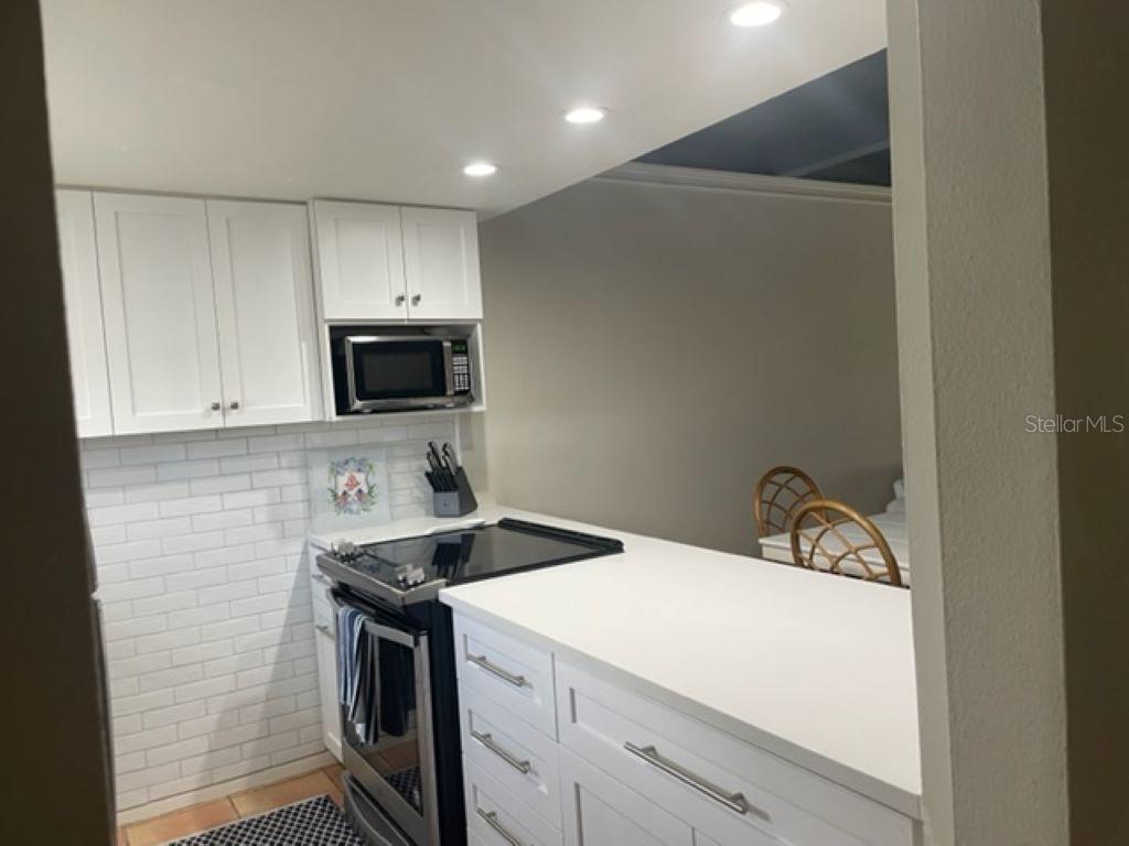 A kitchen features white cabinets, a white subway tile backsplash, and a white countertop — 4849 SAXON DRIVE UNIT C102, NEW SMYRNA BEACH, FL