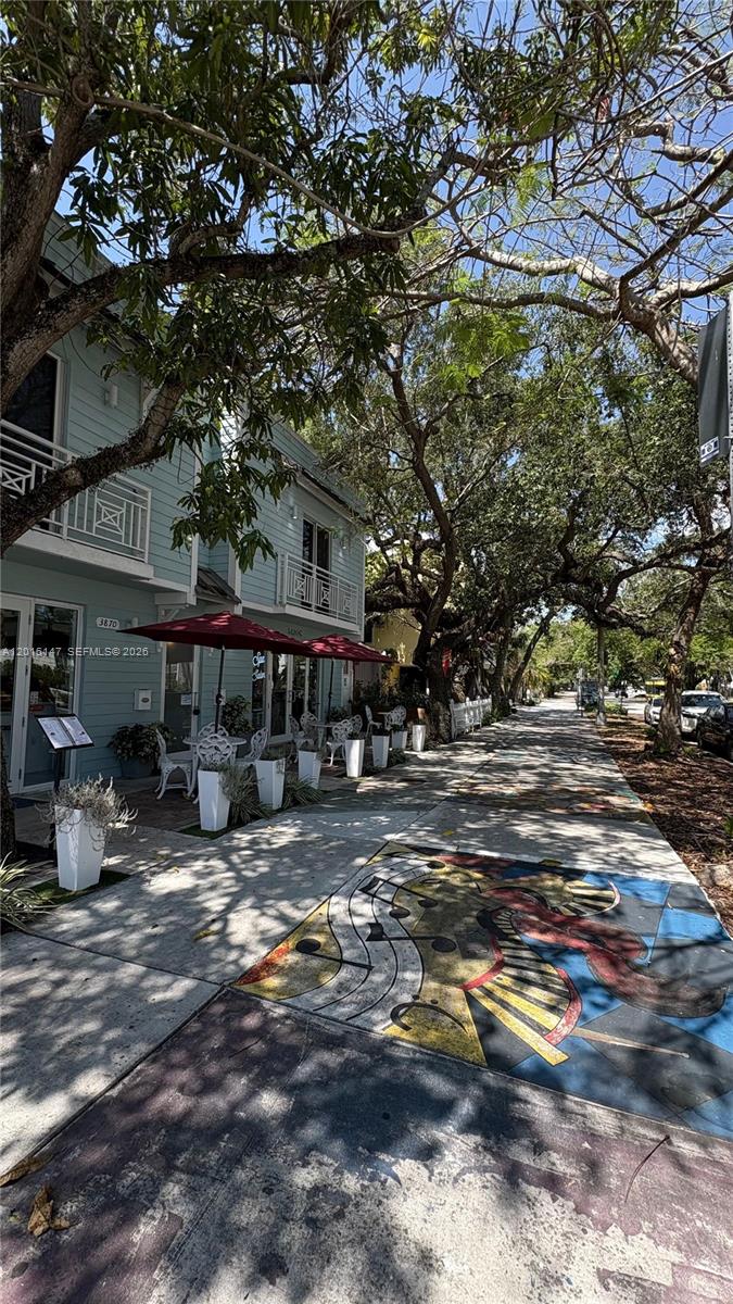 A sidewalk with painted musical art leads past a light blue building with outdoor seating — 3872 Grand Ave # A, Miami FL 33133, MIAMI, FL