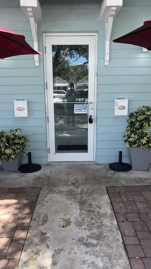 A glass-paned door is flanked by two white mailboxes and potted plants on a patio — 3872 Grand Ave # A, Miami FL 33133, MIAMI, FL