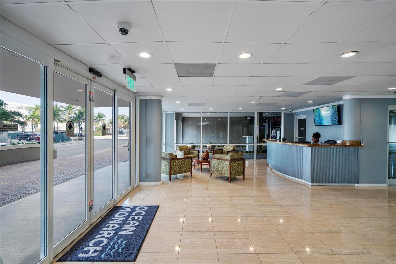 A hotel lobby features a reception desk, seating area, tile floors, and glass entrance doors — 133 N Pompano Beach Boulevard # 806, Pompano Beach FL 33062, POMPANO BEACH, FL