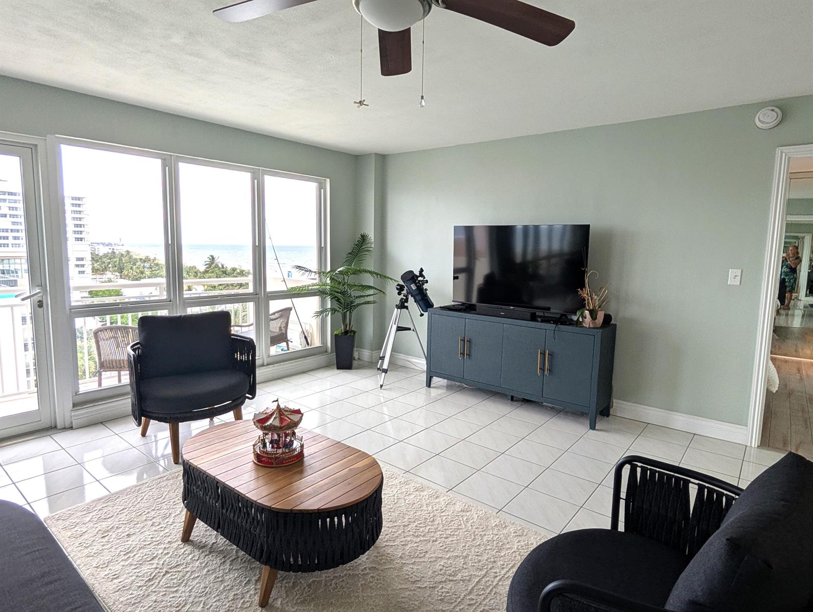 A living room with tile floors, a television on a blue cabinet, and ocean views — 133 N Pompano Beach Boulevard # 806, Pompano Beach FL 33062, POMPANO BEACH, FL