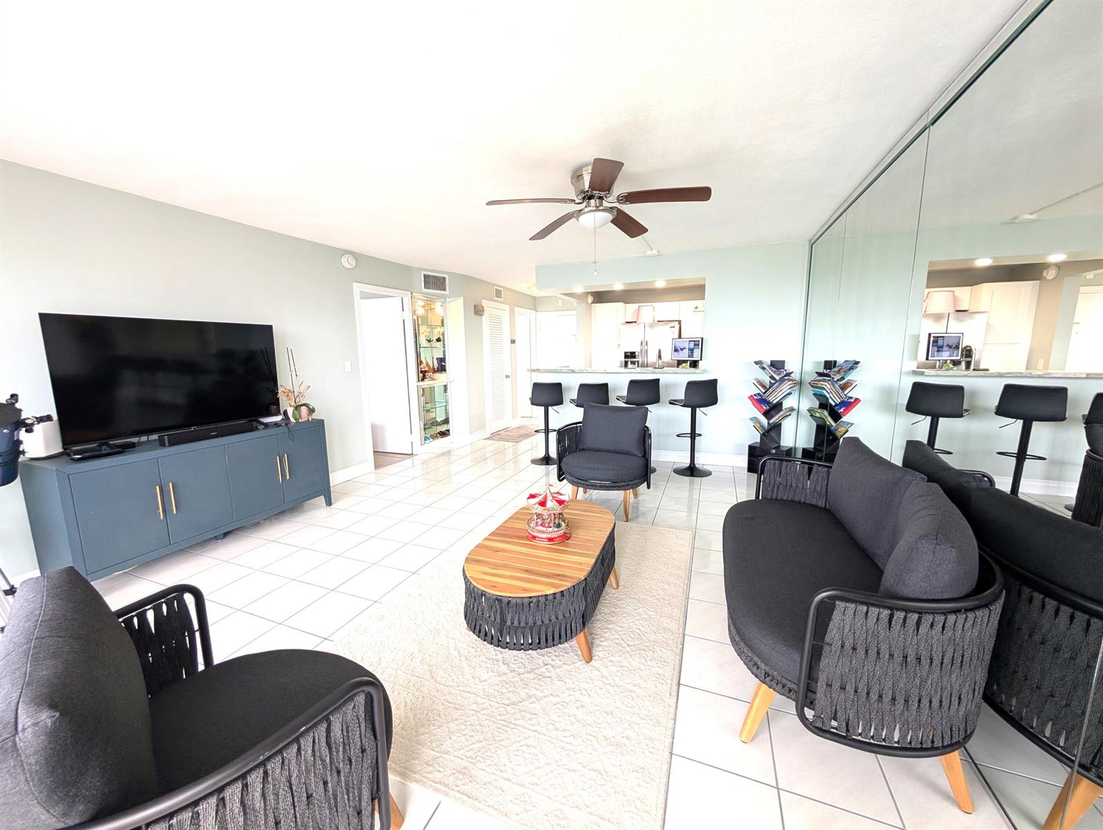 A living room with tile floors, a dark blue media console, and modern charcoal furniture — 133 N Pompano Beach Boulevard # 806, Pompano Beach FL 33062, POMPANO BEACH, FL