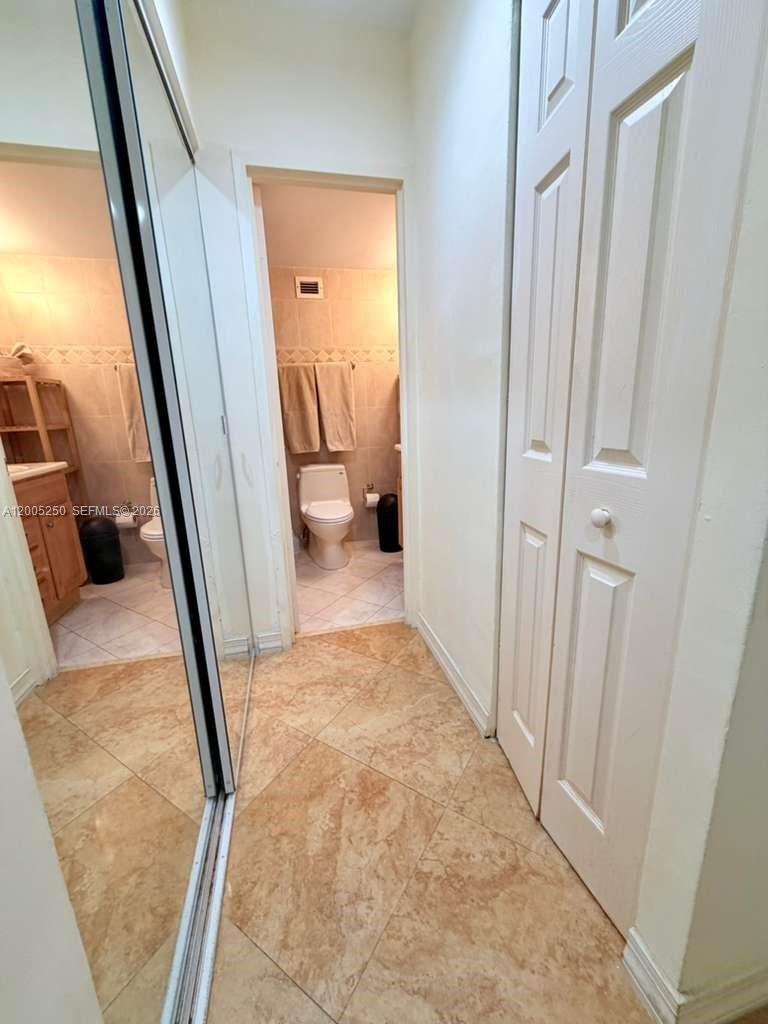 A hallway with tiled floors leads to a bathroom with a toilet and vanity — 100 Lincoln Rd # 534, Miami Beach FL 33139, MIAMI BEACH, FL