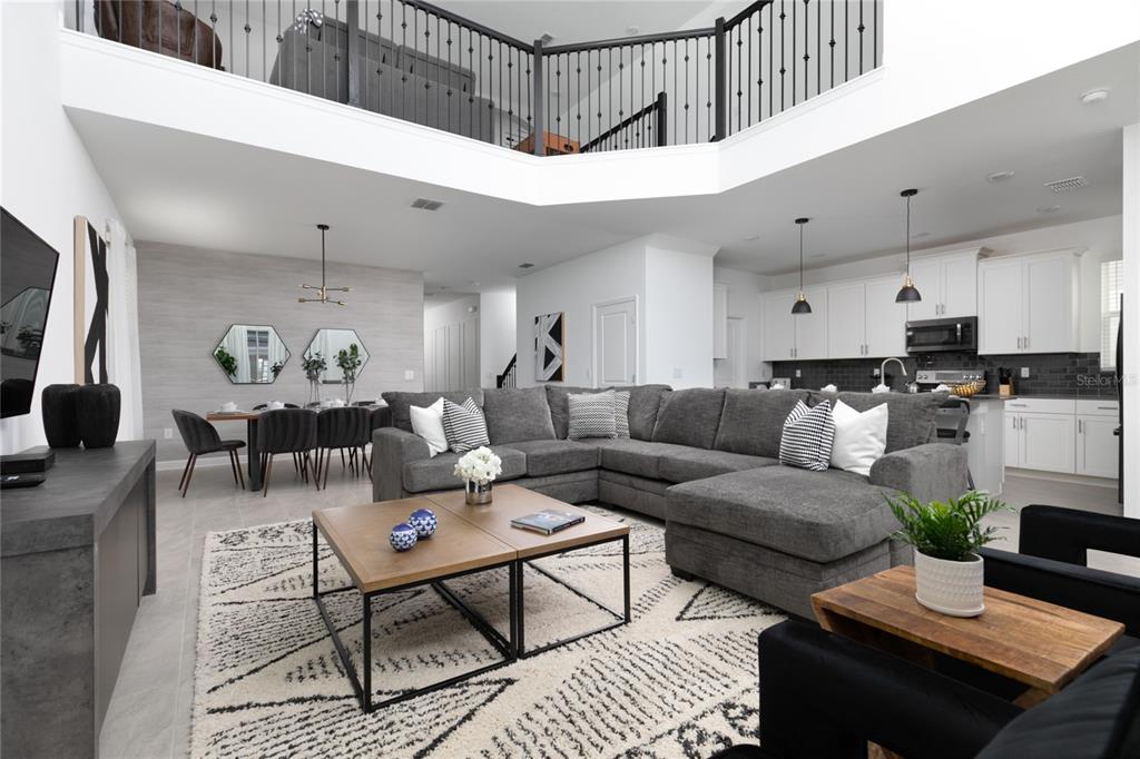 A spacious open-concept living area features a large gray sectional, dining space, and kitchen — 4290 PARAGRAPH DR, KISSIMMEE, FL