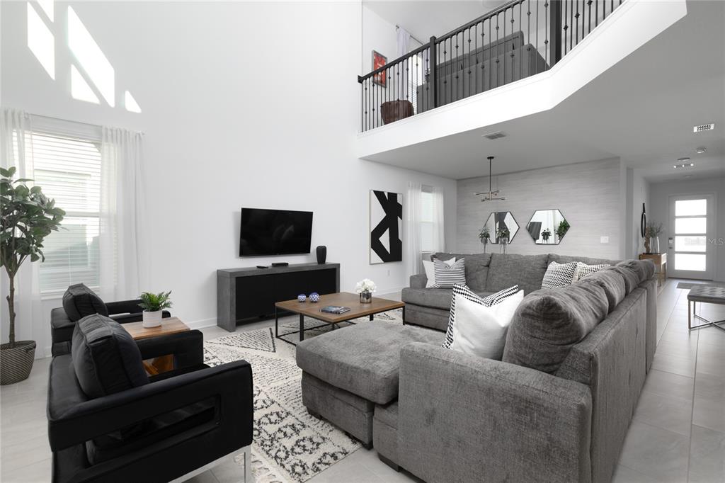 A living room with high ceilings, a grey sectional sofa, and a black media console — 4290 PARAGRAPH DR, KISSIMMEE, FL