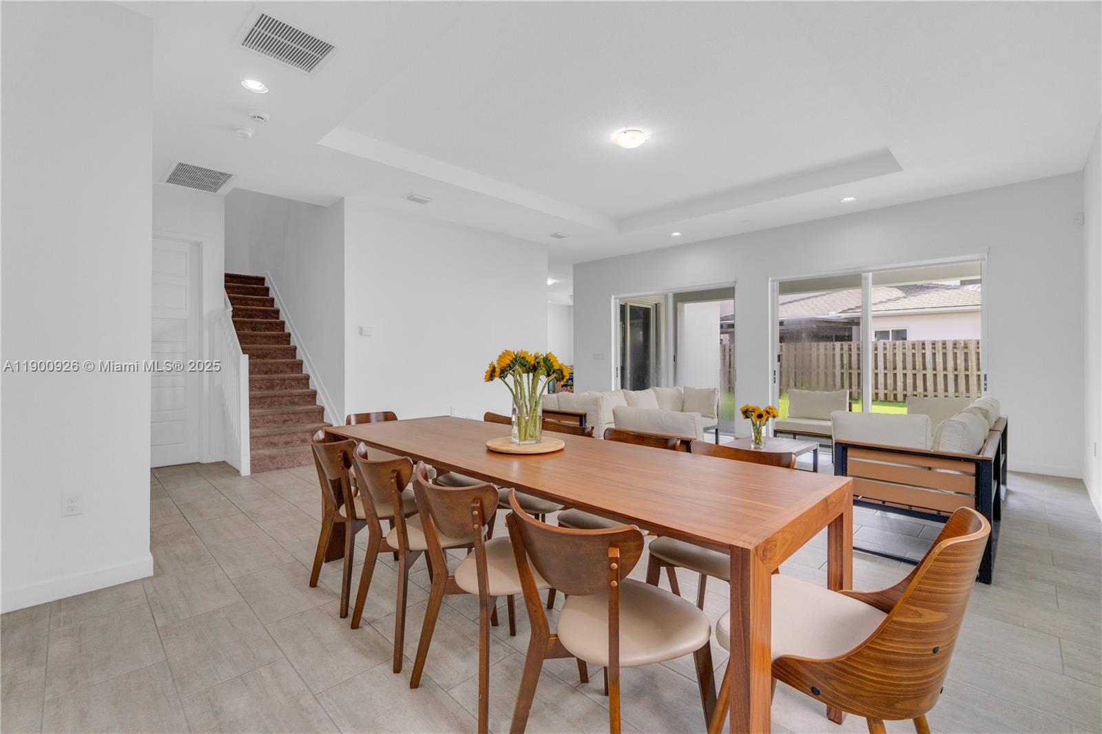 A dining area with a wooden table and chairs sits in front of a living room — 15288 SW 176th Ter, Miami FL 33187, MIAMI, FL