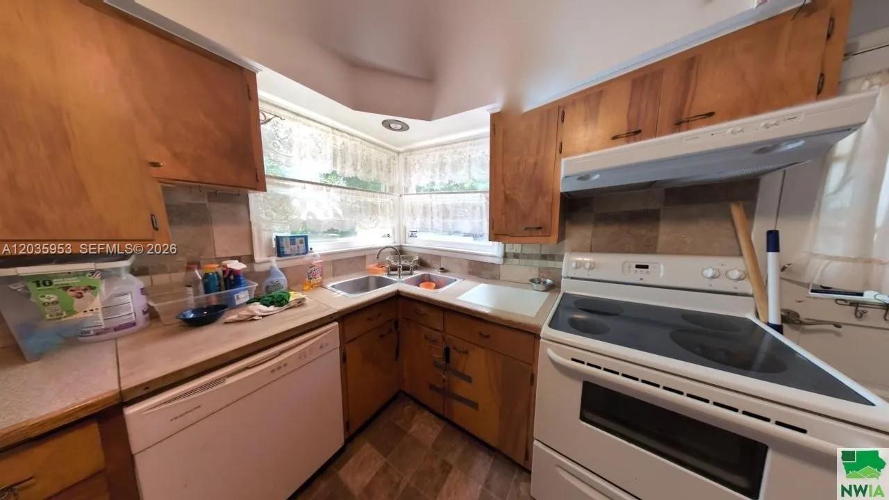 A kitchen features wood cabinets, a white stove, a corner sink, and tiled backsplashes — 35 Hinshaw St, IA 51331, IA