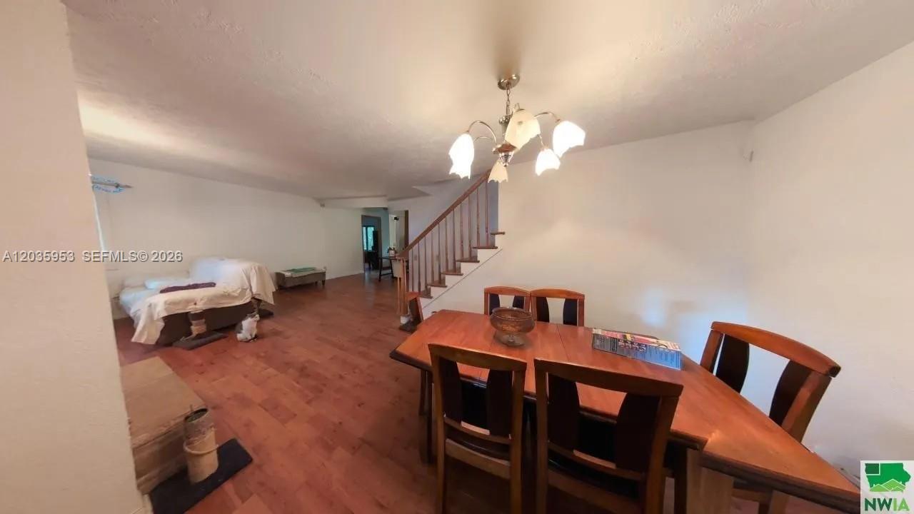 A dining area with a wooden table and chairs sits before a staircase and living space — 35 Hinshaw St, IA 51331, IA