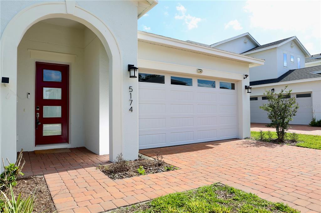 A red front door and a white garage door are visible on this house exterior — 5174 BUTTONSAGE DRIVE, ST CLOUD, FL