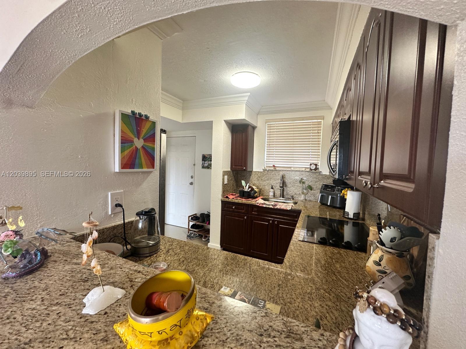 A kitchen features dark wood cabinets, granite countertops, and a pass-through window — MIAMI, FL