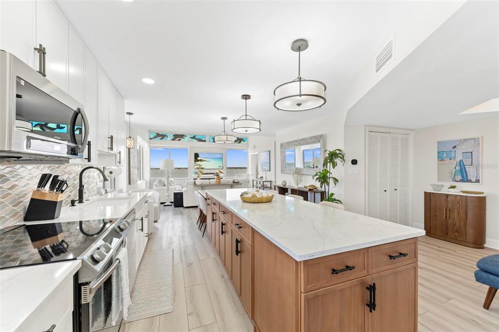 A modern kitchen features a large marble-topped island, light wood cabinetry, and stainless steel appliances — 5153 ISLA KEY BOULEVARD S UNIT 408, ST PETERSBURG, FL