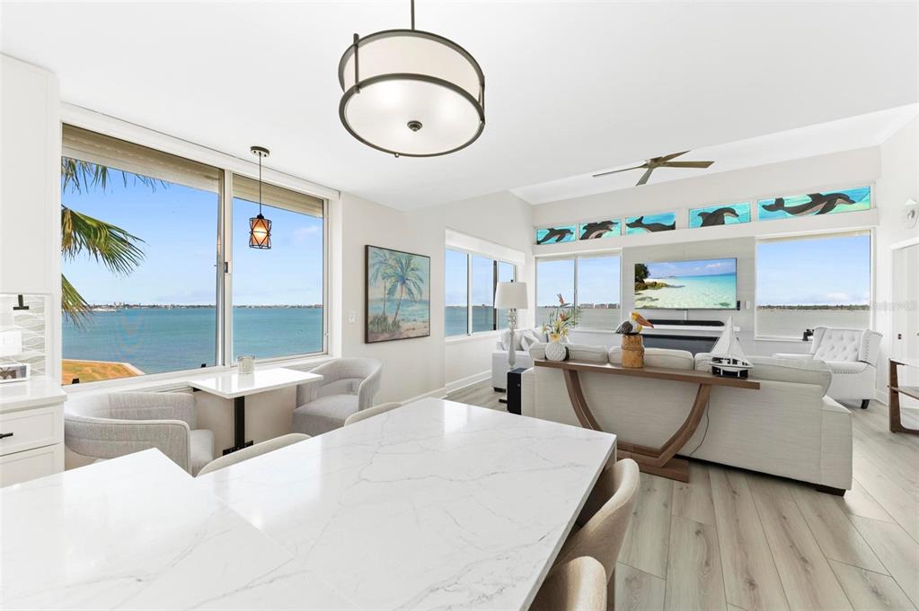 A bright, open-concept living and dining area features marble countertops, water views, and coastal decor — 5153 ISLA KEY BOULEVARD S UNIT 408, ST PETERSBURG, FL
