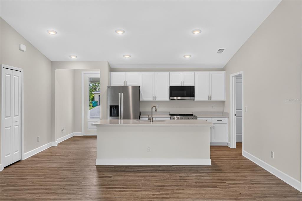 A modern kitchen features white cabinetry, stainless steel appliances, and a central island with seating — 147 FLANDERS STREET, PORT CHARLOTTE, FL
