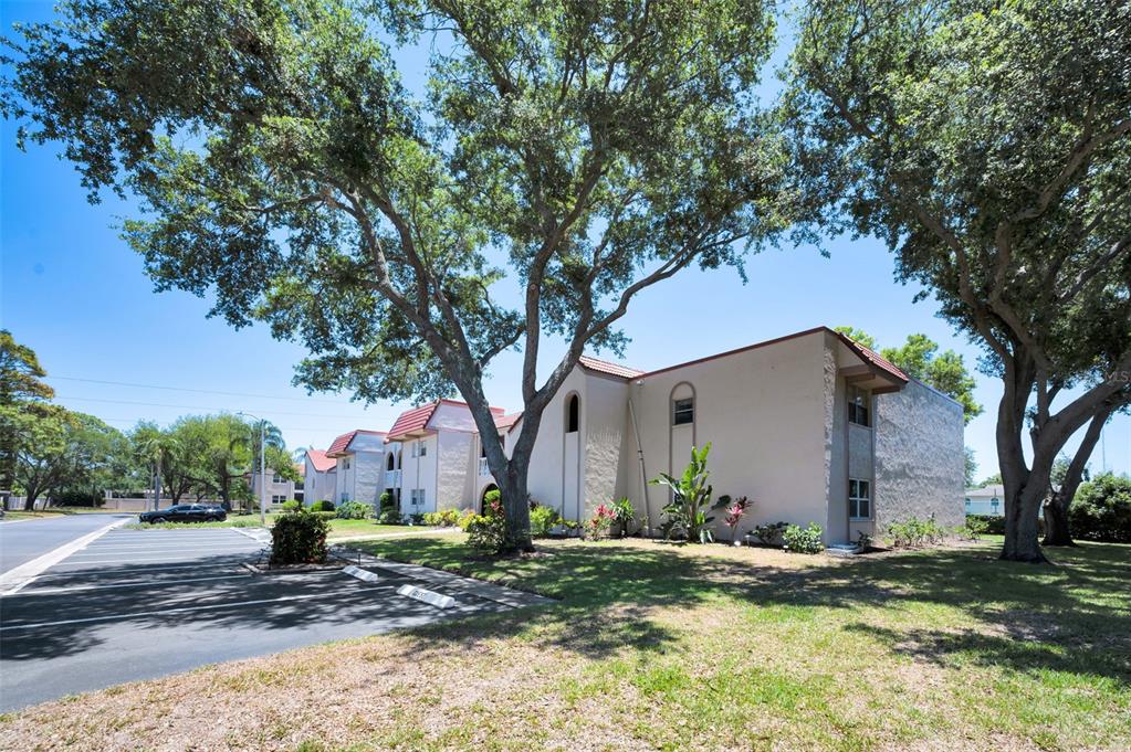 A multi-story apartment building with a parking lot and large trees in the foreground — 9700 STARKEY ROAD UNIT 228, SEMINOLE, FL