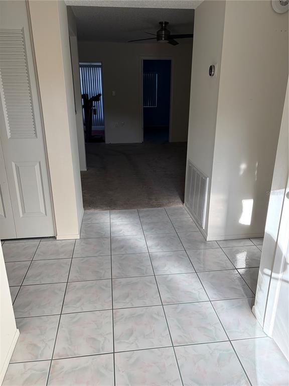 A tiled entryway leads into a carpeted living area with a ceiling fan — 3807 STAYSAIL LANE UNIT 3807, HOLIDAY, FL