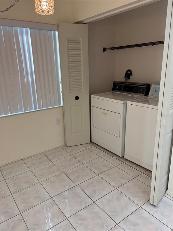 A laundry room features tile flooring, a window with vertical blinds, and a washer-dryer set — 3807 STAYSAIL LANE UNIT 3807, HOLIDAY, FL