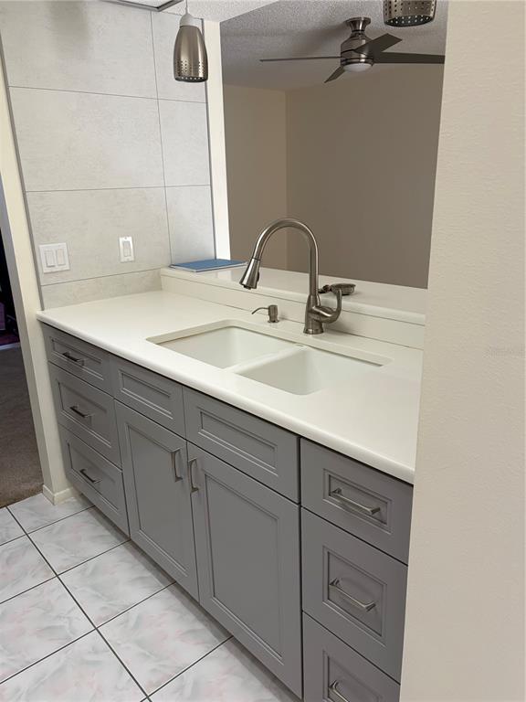 A kitchen sink area features gray cabinets, a white countertop, and a tiled backsplash — 3807 STAYSAIL LANE UNIT 3807, HOLIDAY, FL