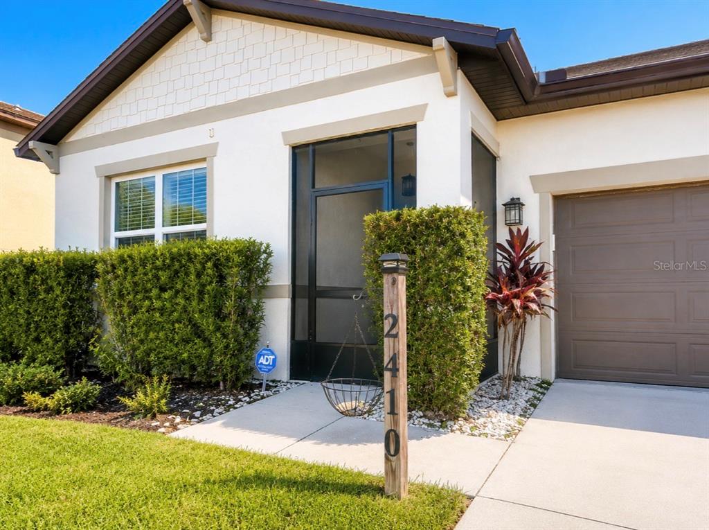 The exterior of a house features a screened entryway, a garage, and a house number post — 2410 BITTLE WAY, ST CLOUD, FL