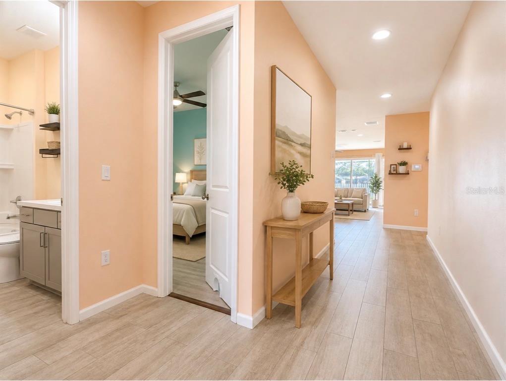A hallway with light wood-look tile flooring leads to a living area and bedroom — 2410 BITTLE WAY, ST CLOUD, FL