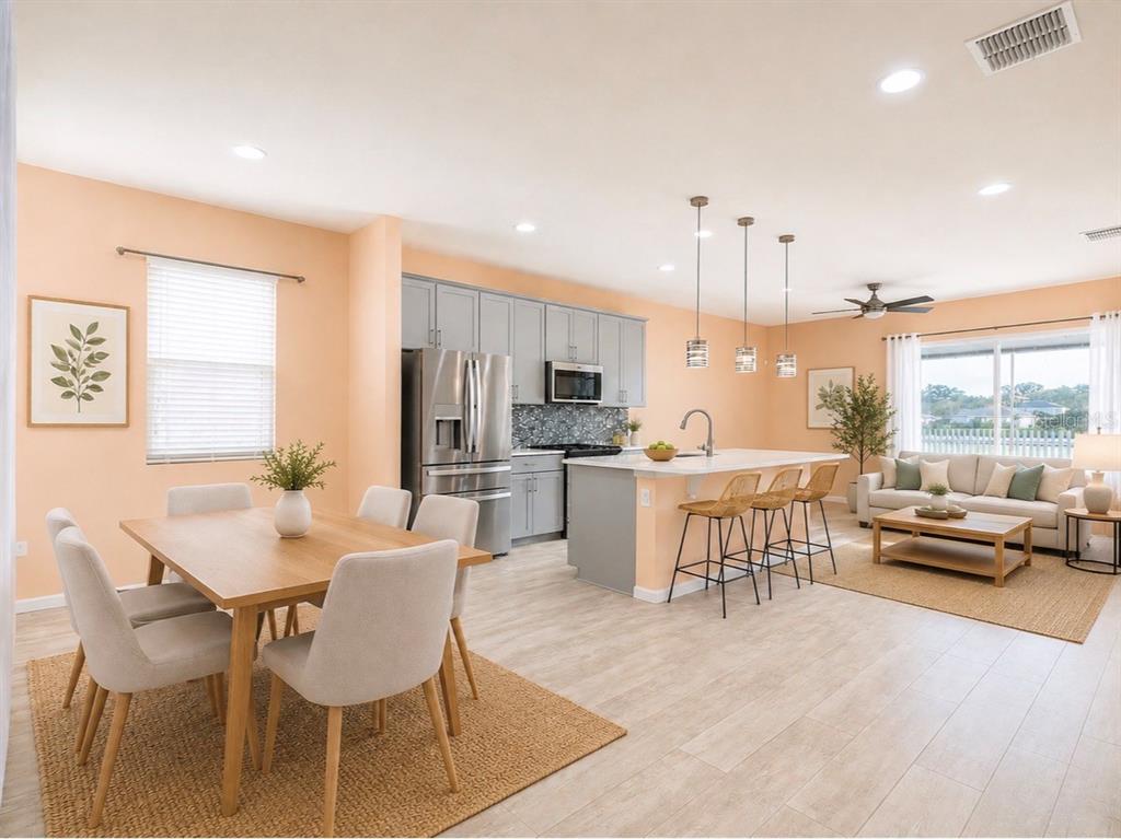 An open-concept kitchen, dining area, and living room featuring light wood floors and peach walls — 2410 BITTLE WAY, ST CLOUD, FL