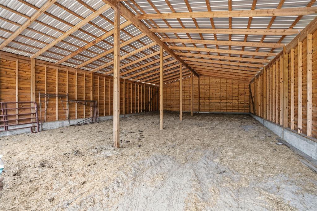 An open-sided pole barn with a dirt floor, wooden walls, and a metal roof — 14405 AMY LANE, HUDSON, FL