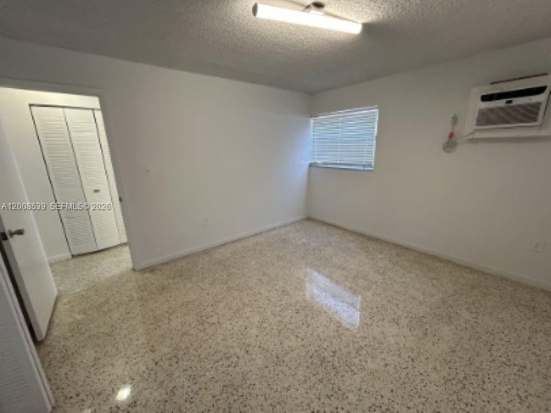 An empty bedroom features white walls, a window with blinds, a wall-mounted air conditioner, and terrazzo flooring — 142 SW 18th Ave # 20, Miami FL 33135, MIAMI, FL
