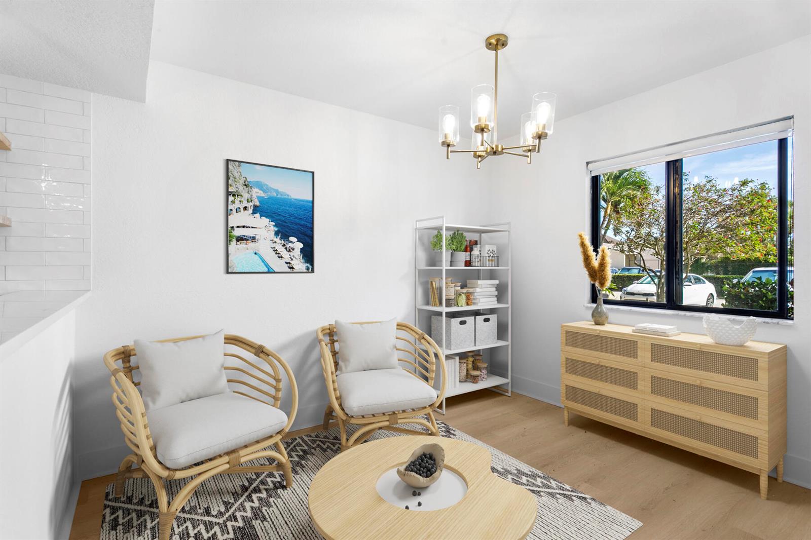 A bright living room features two rattan chairs, a wooden dresser, and a modern chandelier — 601 Seafarer Circle # 101, Jupiter FL 33477, JUPITER, FL