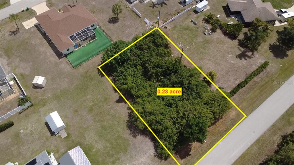 An aerial view shows a rectangular, tree-covered vacant lot outlined in yellow — 7250 PEACOCK LANE, ENGLEWOOD, FL