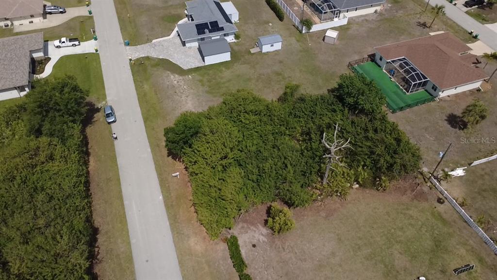 An aerial view shows a vacant, tree-covered lot situated between two residential properties — 7250 PEACOCK LANE, ENGLEWOOD, FL