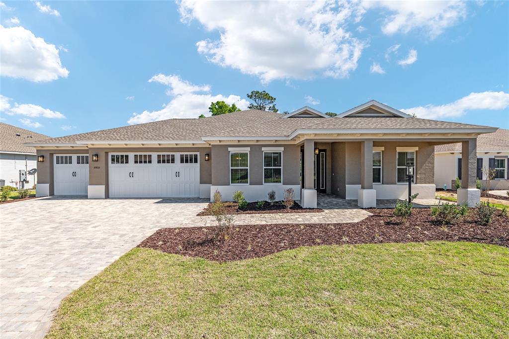 A single-story house features a paved driveway, a three-car garage, and a covered front porch — 10815 SW 96TH LANE ROAD, OCALA, FL