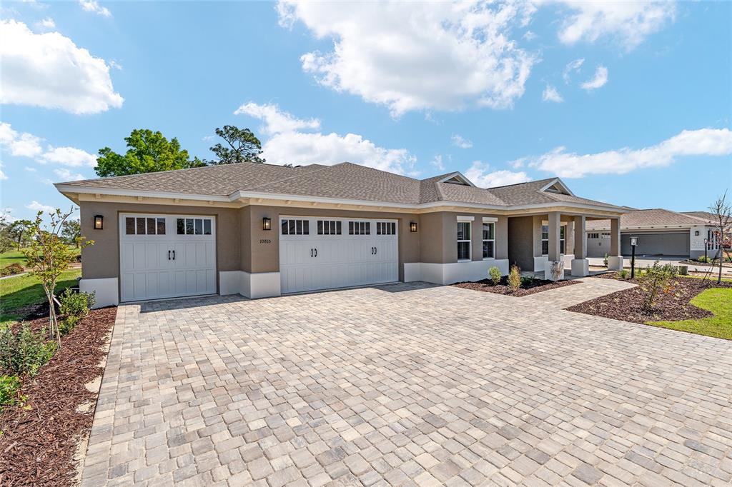 A single-story house with a three-car garage and a paved driveway under a blue sky — 10815 SW 96TH LANE ROAD, OCALA, FL