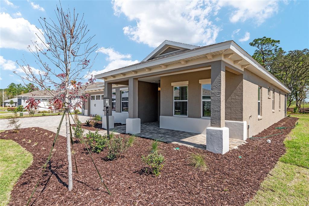 A single-story house with a covered front porch, tan stucco siding, and a paved driveway — 10815 SW 96TH LANE ROAD, OCALA, FL